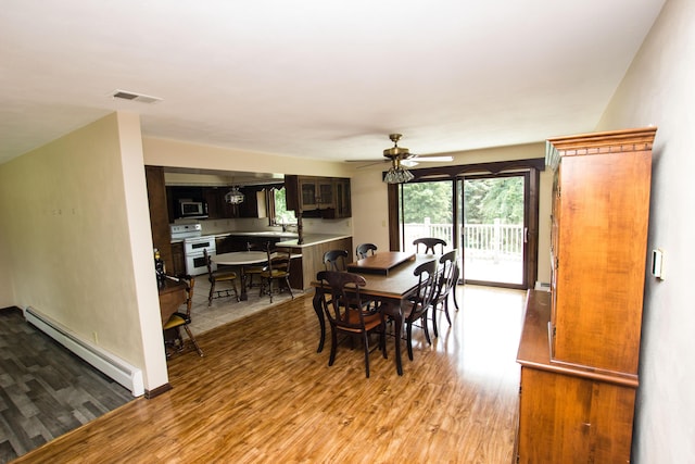 dining space with ceiling fan, a baseboard radiator, sink, and light hardwood / wood-style flooring