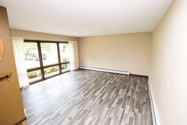 spare room featuring wood-type flooring and baseboard heating