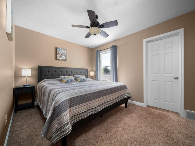 carpeted bedroom featuring a textured ceiling and ceiling fan