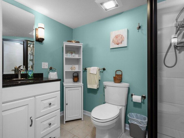 bathroom featuring tile patterned flooring, toilet, walk in shower, and vanity