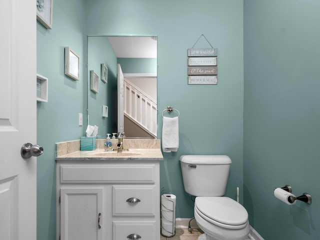 bathroom featuring baseboards, toilet, and vanity