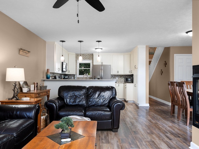 living area with stairway, a ceiling fan, wood finished floors, baseboards, and a toaster