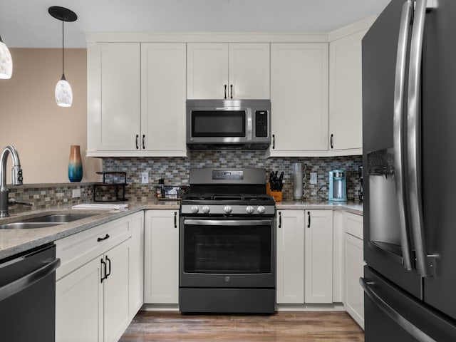 kitchen featuring light wood-type flooring, decorative backsplash, stainless steel appliances, white cabinetry, and a sink