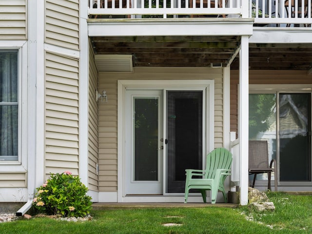 property entrance with a lawn and a balcony