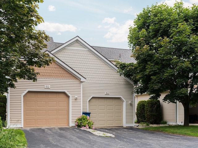 view of front of property featuring an attached garage, driveway, and a shingled roof