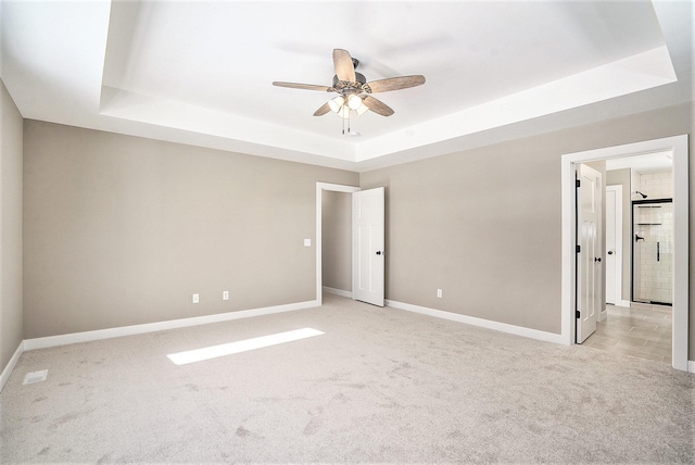 carpeted spare room with a tray ceiling and ceiling fan