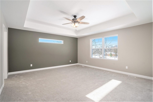 spare room with carpet, a tray ceiling, and ceiling fan