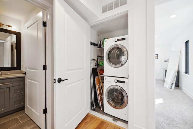 laundry area featuring carpet, sink, and stacked washer and clothes dryer