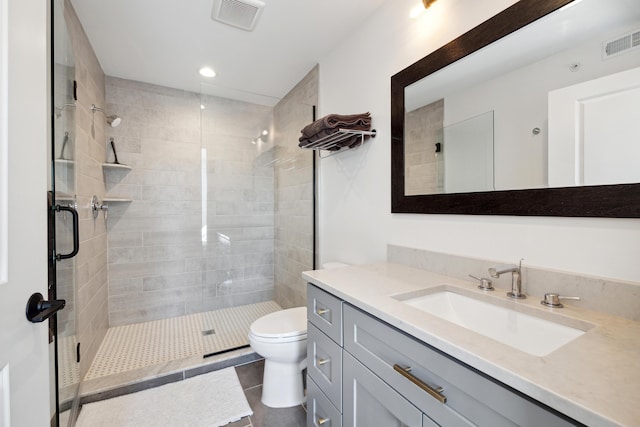 bathroom featuring tile patterned flooring, vanity, toilet, and an enclosed shower