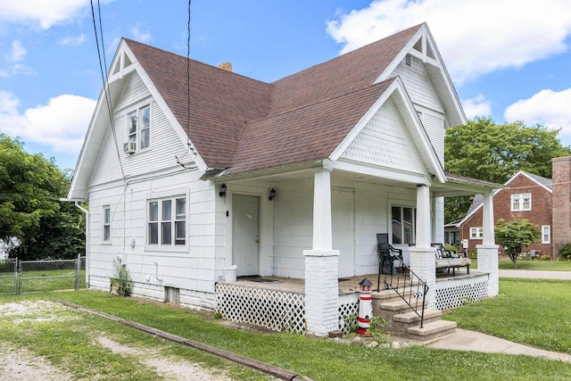 view of front of property with a shingled roof, a chimney, covered porch, fence, and a front yard