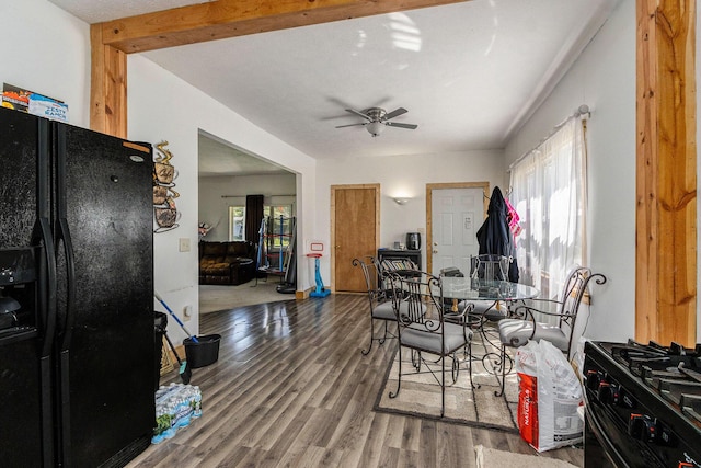 dining space featuring a ceiling fan, wood finished floors, and beamed ceiling