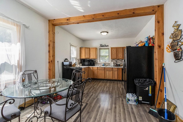 kitchen featuring dark wood-style flooring, light countertops, beam ceiling, brown cabinets, and black appliances