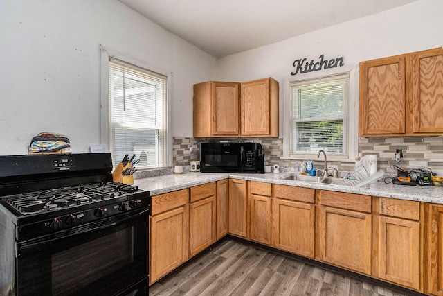 kitchen featuring tasteful backsplash, a sink, light wood-style floors, and black appliances