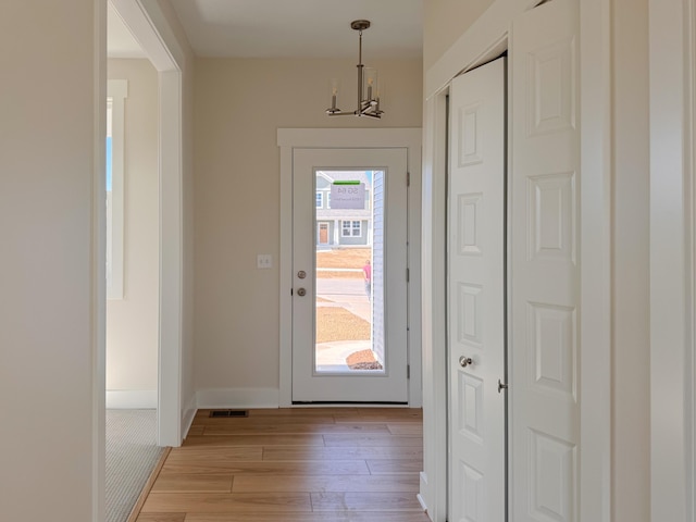 doorway featuring a notable chandelier, a healthy amount of sunlight, and light hardwood / wood-style floors