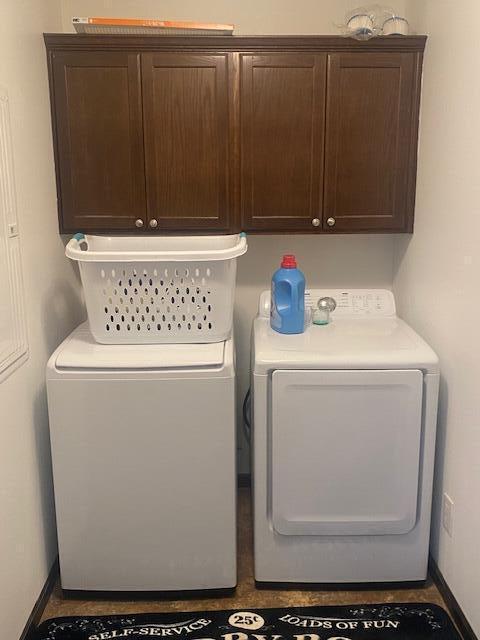 clothes washing area featuring cabinets and separate washer and dryer