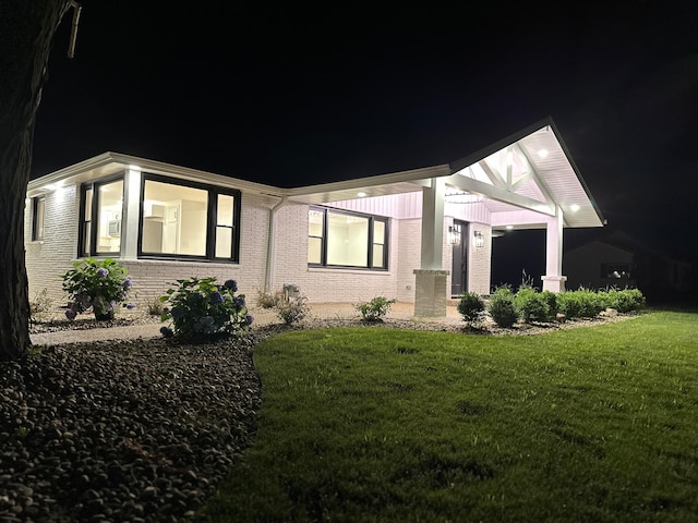 property exterior at night with a lawn