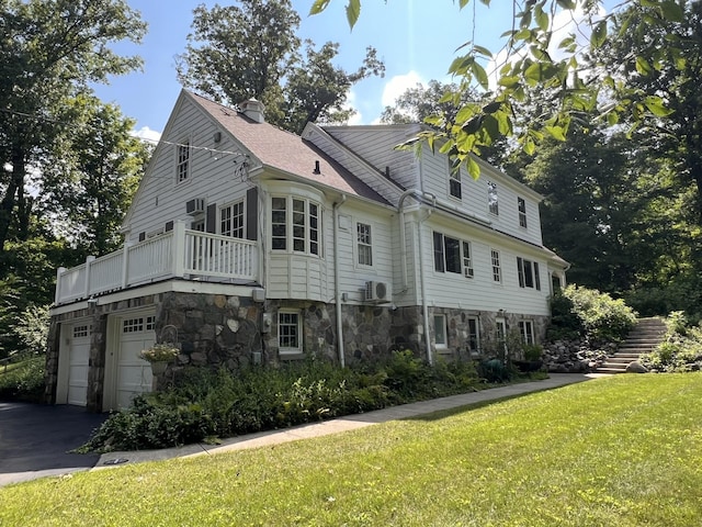 view of side of property with a garage, a balcony, and a lawn