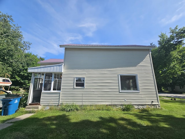 view of property exterior featuring a sunroom and a lawn