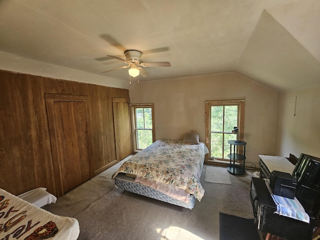 carpeted bedroom with ceiling fan, lofted ceiling, and wooden walls