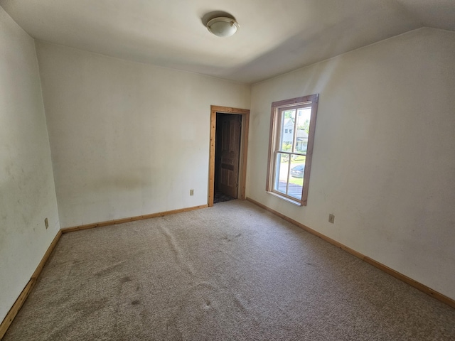 carpeted spare room featuring lofted ceiling