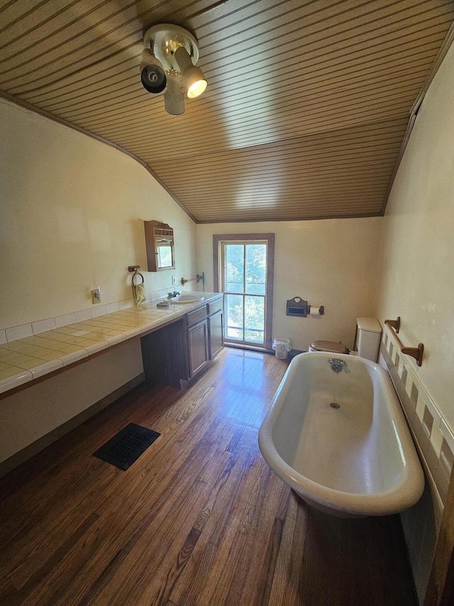 bathroom with wood ceiling, vaulted ceiling, vanity, hardwood / wood-style floors, and a washtub