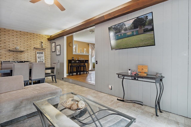 living room featuring wooden walls, ceiling fan, and brick wall