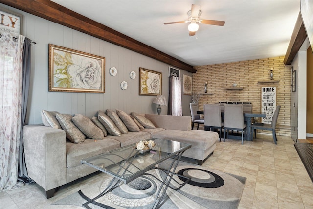 living room featuring beamed ceiling, brick wall, wooden walls, and ceiling fan