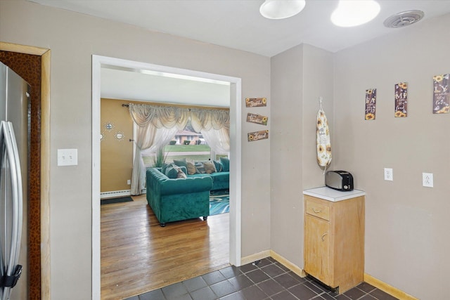 corridor with dark tile patterned flooring and baseboard heating