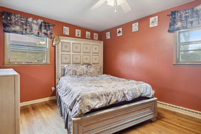 bedroom with baseboard heating, ceiling fan, and light wood-type flooring