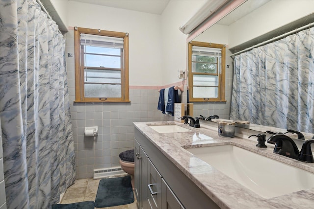 bathroom featuring tile walls, tile patterned flooring, a baseboard heating unit, vanity, and toilet