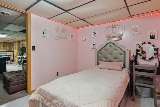 bedroom featuring a paneled ceiling and wooden walls