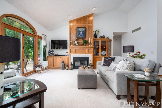 carpeted living room with high vaulted ceiling, a textured ceiling, and a fireplace