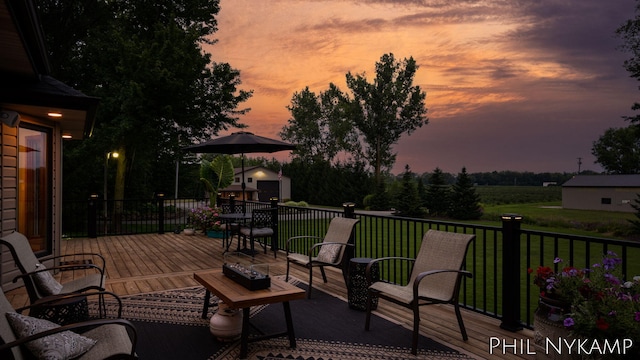 patio terrace at dusk with a wooden deck, a yard, and a storage unit