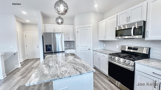 kitchen with tasteful backsplash, stainless steel appliances, a kitchen island, and white cabinets