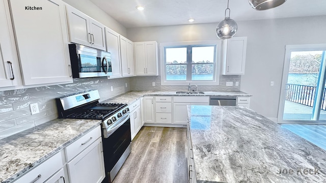 kitchen featuring sink, stainless steel appliances, white cabinets, and light stone countertops