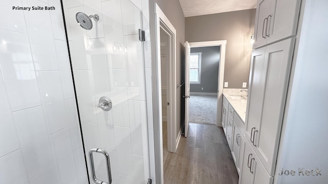 bathroom with vanity, a shower with shower door, and hardwood / wood-style floors