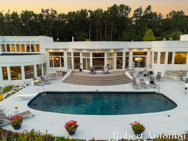 pool at dusk featuring a patio