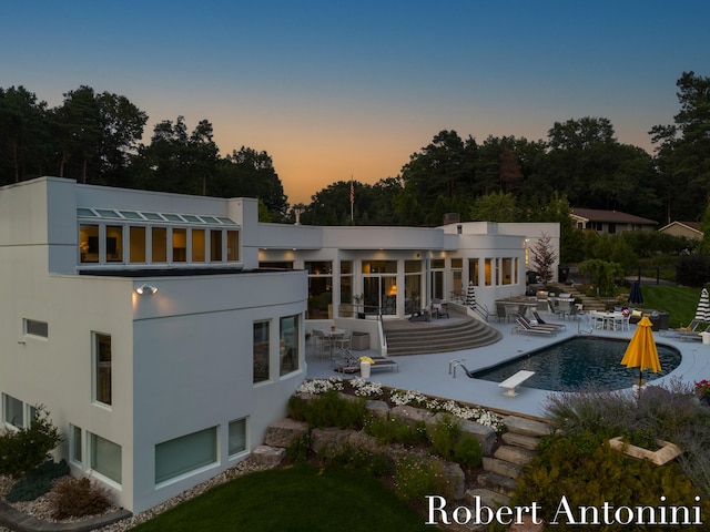 back house at dusk featuring a patio area