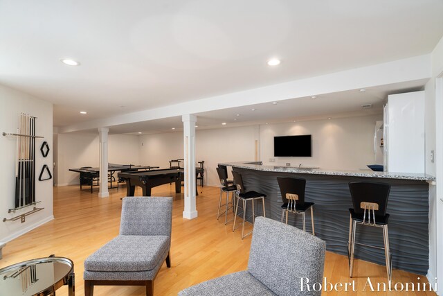 living room featuring bar area, decorative columns, and light hardwood / wood-style floors