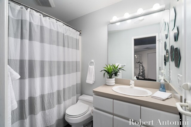 bathroom featuring a shower with shower curtain, toilet, and vanity