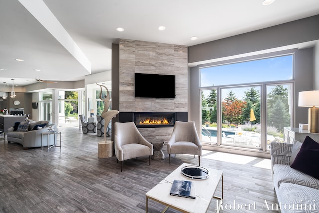 living room with ceiling fan, a tiled fireplace, and dark hardwood / wood-style flooring