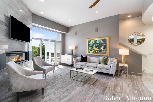 living room featuring wood-type flooring, a fireplace, and ceiling fan