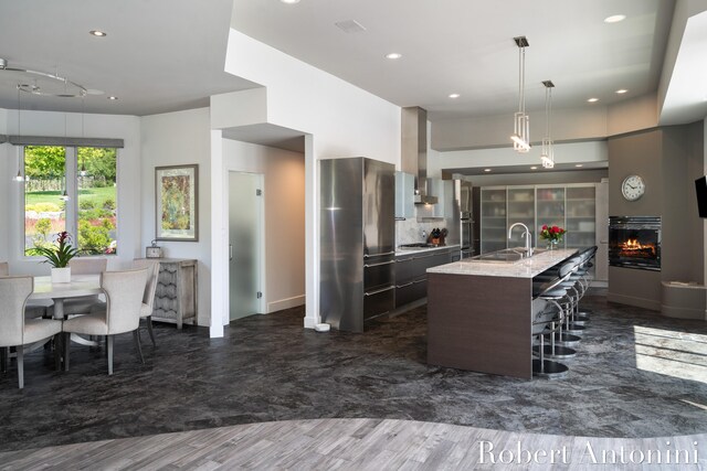 kitchen with dark wood-type flooring, appliances with stainless steel finishes, an island with sink, and sink