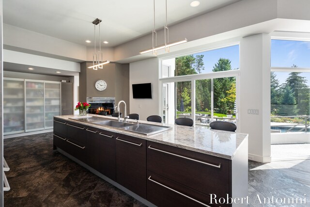 kitchen with a kitchen island with sink, pendant lighting, dark brown cabinets, and sink