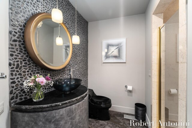 bathroom with a shower with door, vanity, toilet, and decorative backsplash