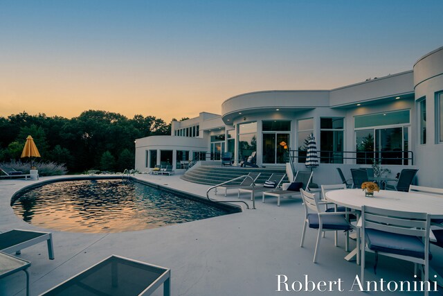 pool at dusk featuring a patio area