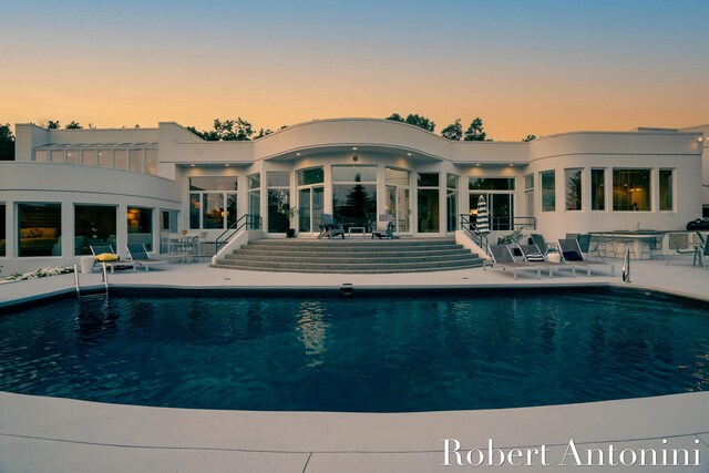 pool at dusk featuring a patio area