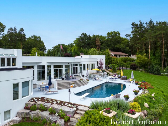 view of swimming pool with a diving board, a lawn, and a patio