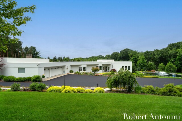 rear view of property with a garage and a lawn