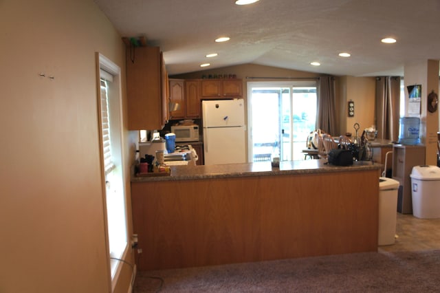 kitchen featuring white appliances, kitchen peninsula, light carpet, and vaulted ceiling